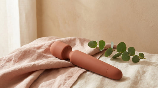 Plusieurs vibromasseurs modernes en silicone posés sur un linge rose poudré, ambiance douce et discrète