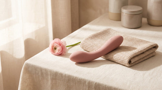 Vibromasseur point G en silicone rose sur lin crème, ambiance wellness premium